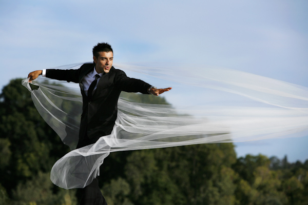Groom caught in bride's veil - wedding photo by Jerry Ghionis